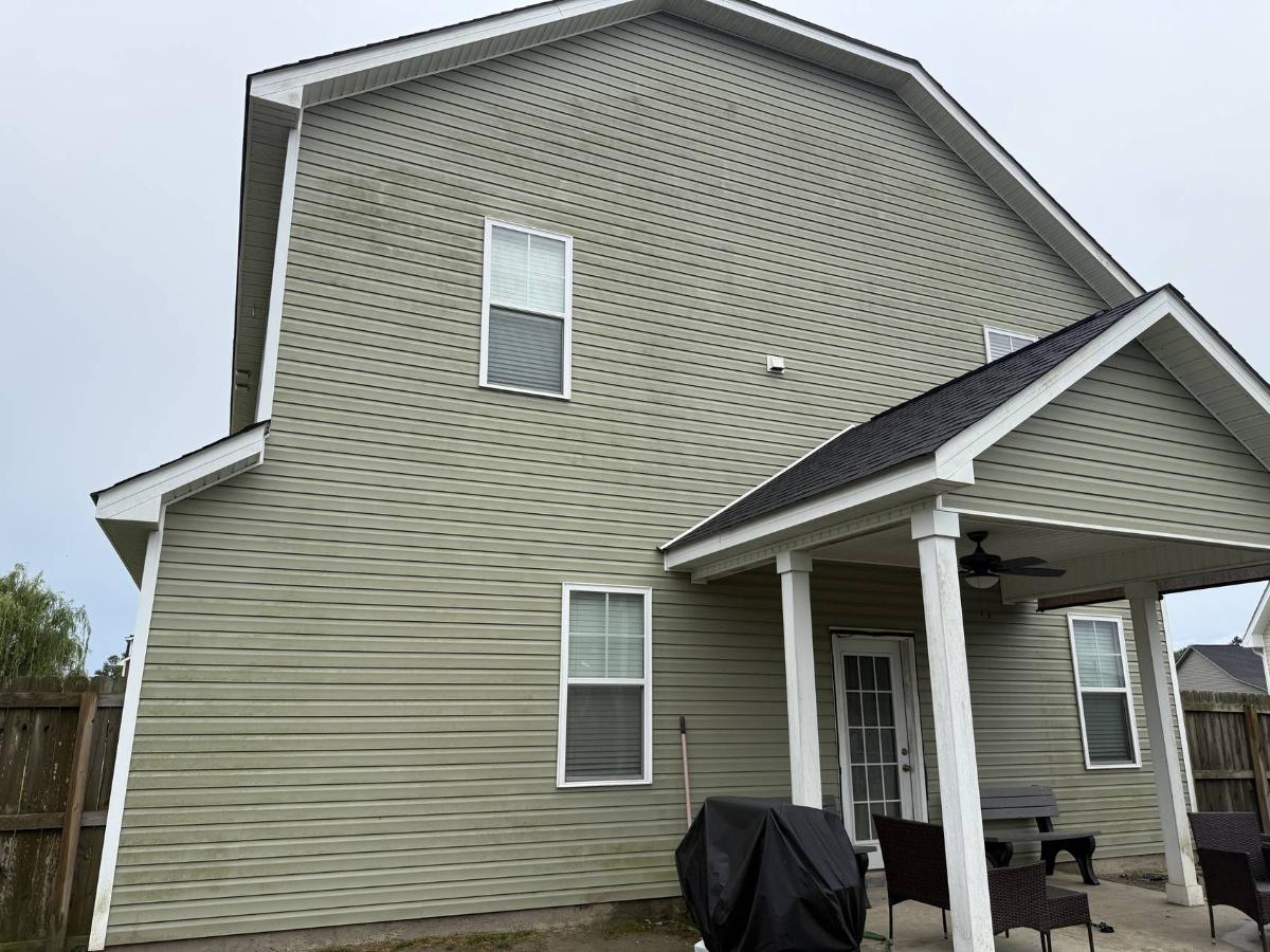 House siding covered in green algae before pressure washing