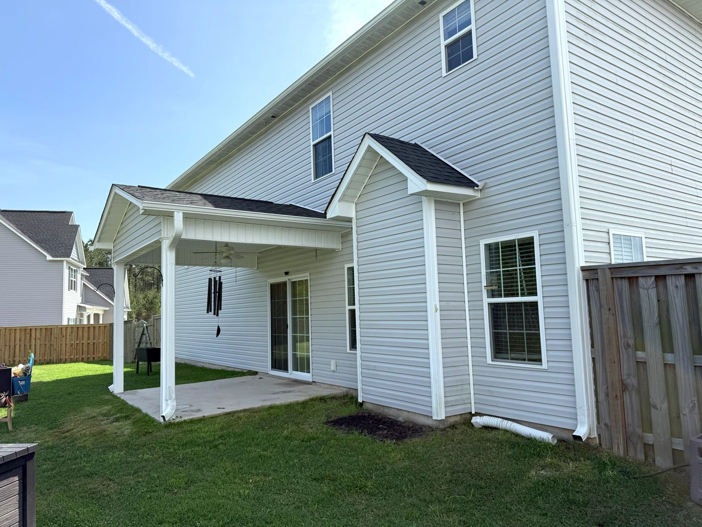 Pressure washing transformed the home's exterior, revealing a clean, bright vinyl siding and patio area, improving overall curb appeal.