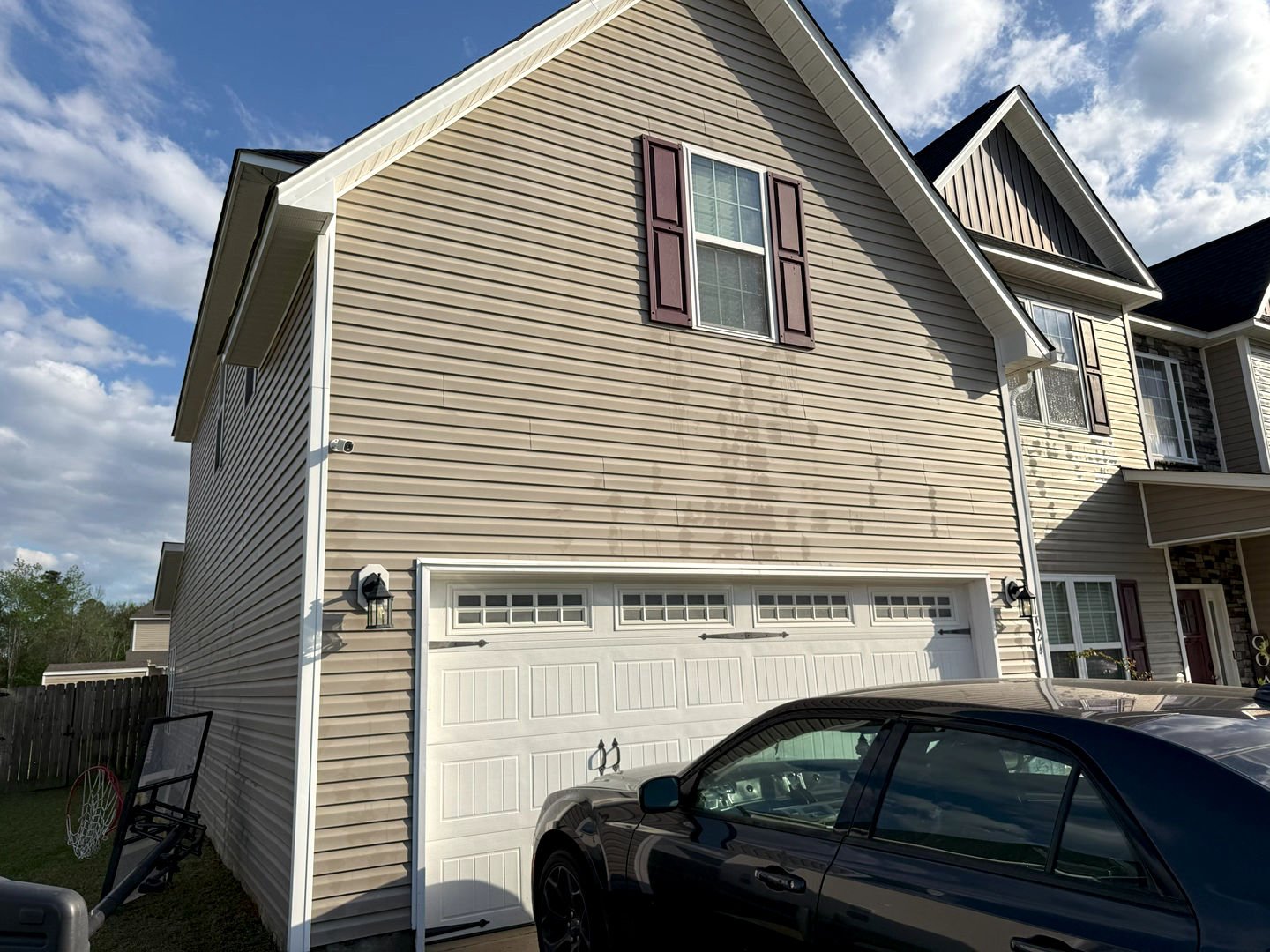 A house with clean vinyl siding after pressure washing, showcasing a dramatic contrast with remaining dirt stains.