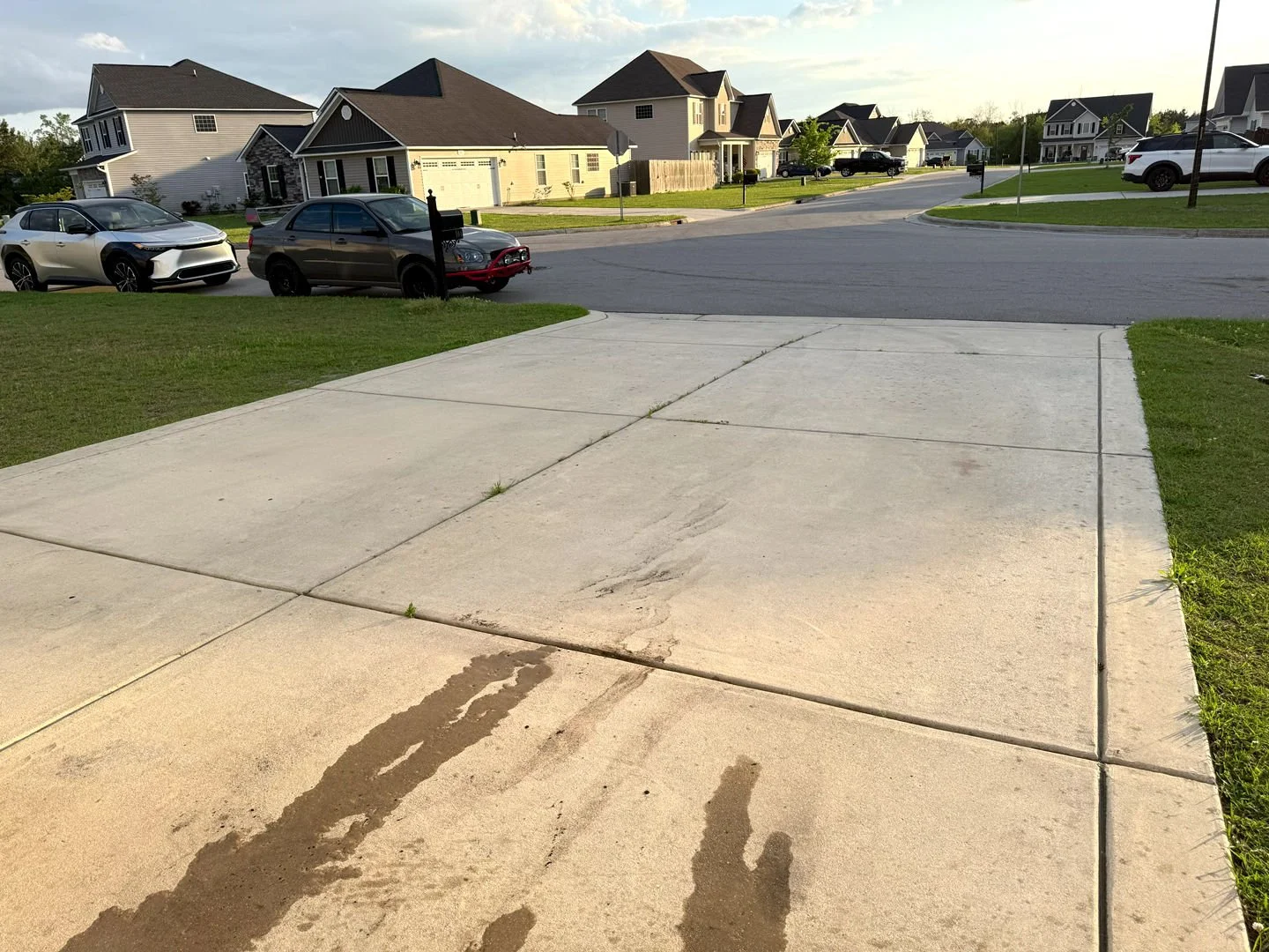 A freshly pressure-washed concrete driveway shows a clean surface free of dirt and grime, enhancing curb appeal in a residential area.