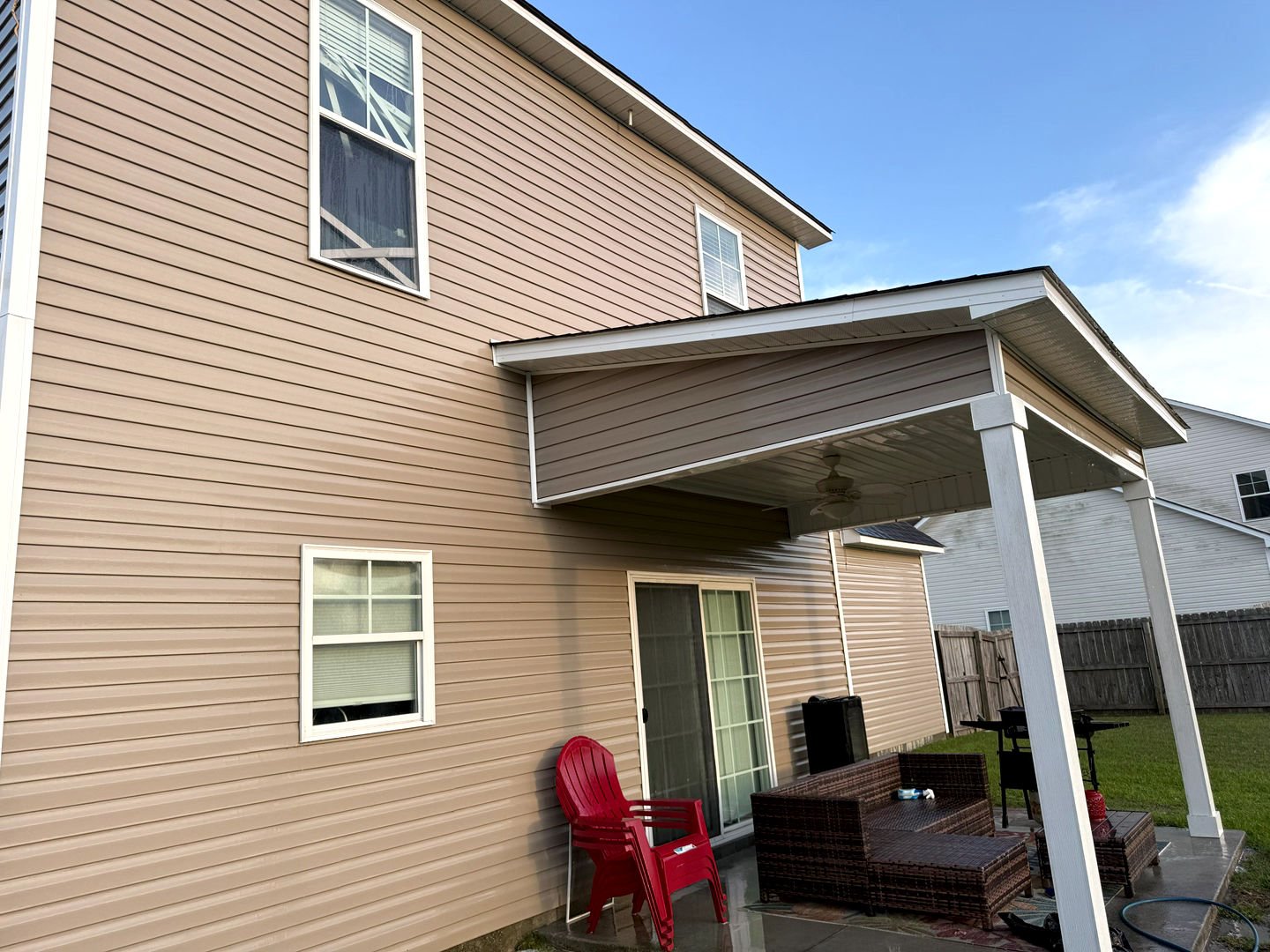 Pressure washing a residential house's vinyl siding, revealing a clean, refreshed appearance free of dirt and grime.