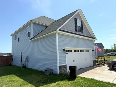 Pressure washing of a residential home exterior, highlighting a clean, refreshed light blue siding with vibrant details.