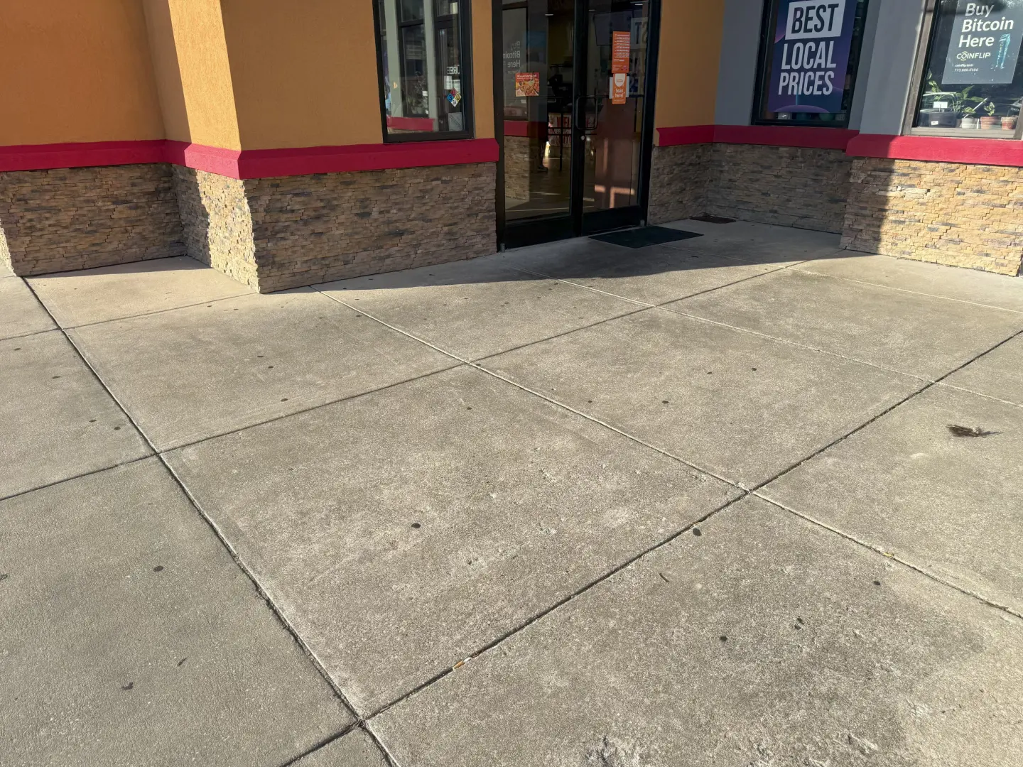 Cleaned concrete entrance sidewalk showing improved appearance with dirt and stains removed from the surface.
