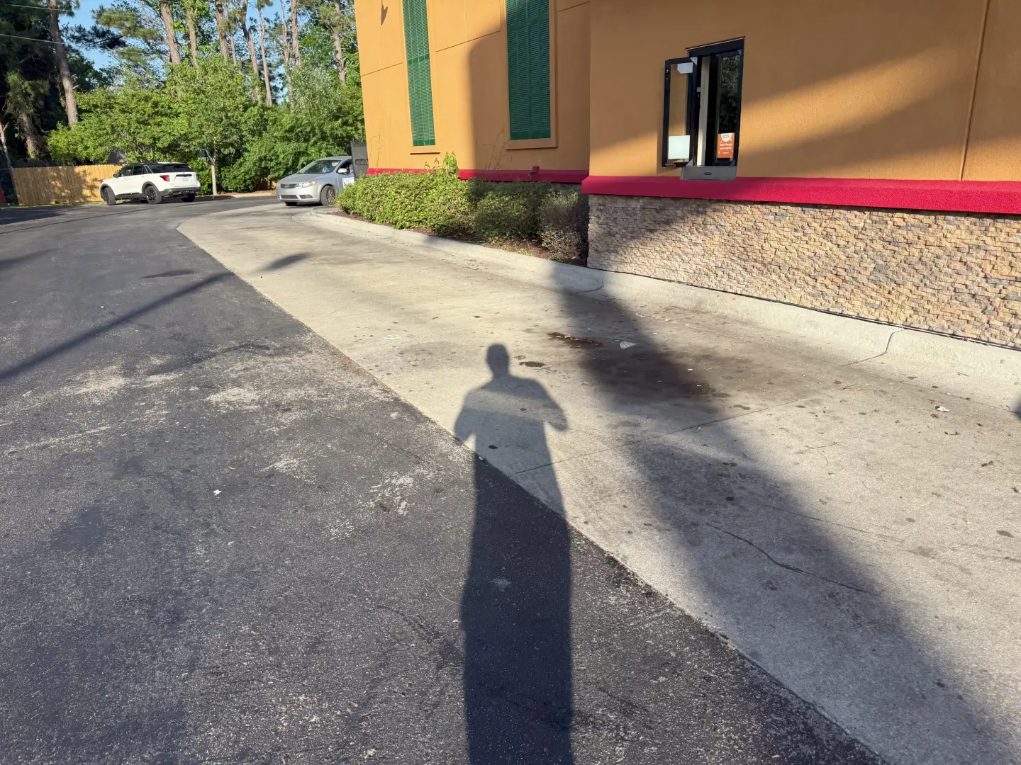 Pressure washing cleans a commercial asphalt driveway, leaving a noticeable contrast between dirt and refreshed surface.