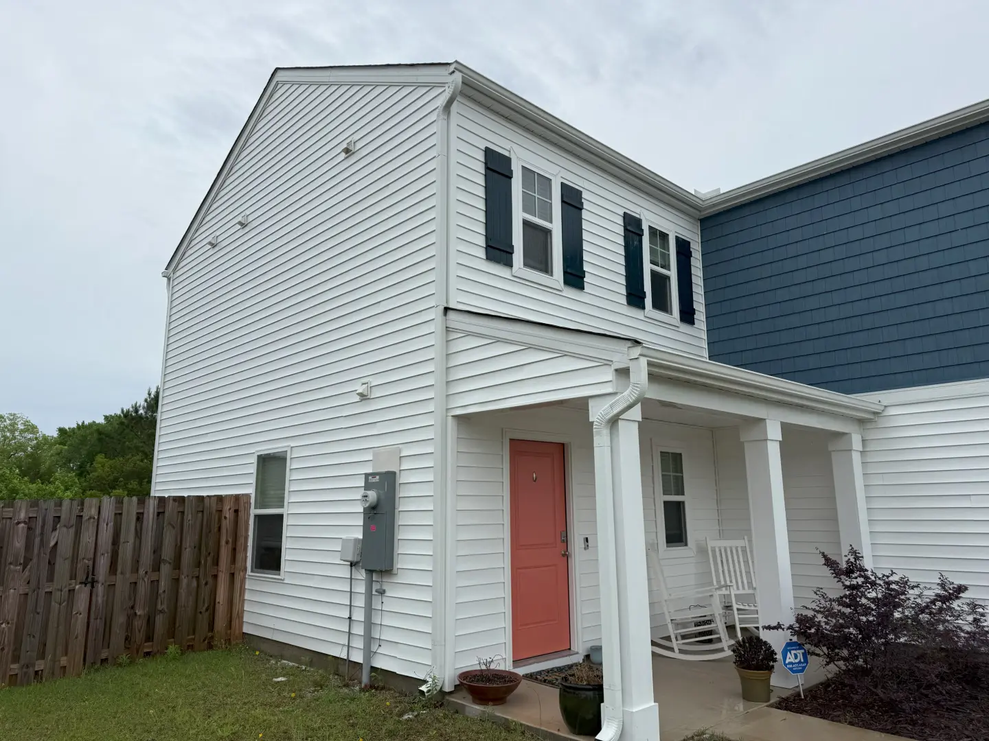 Freshly pressure washed white vinyl siding on a house, showcasing a clean and revitalized exterior.
