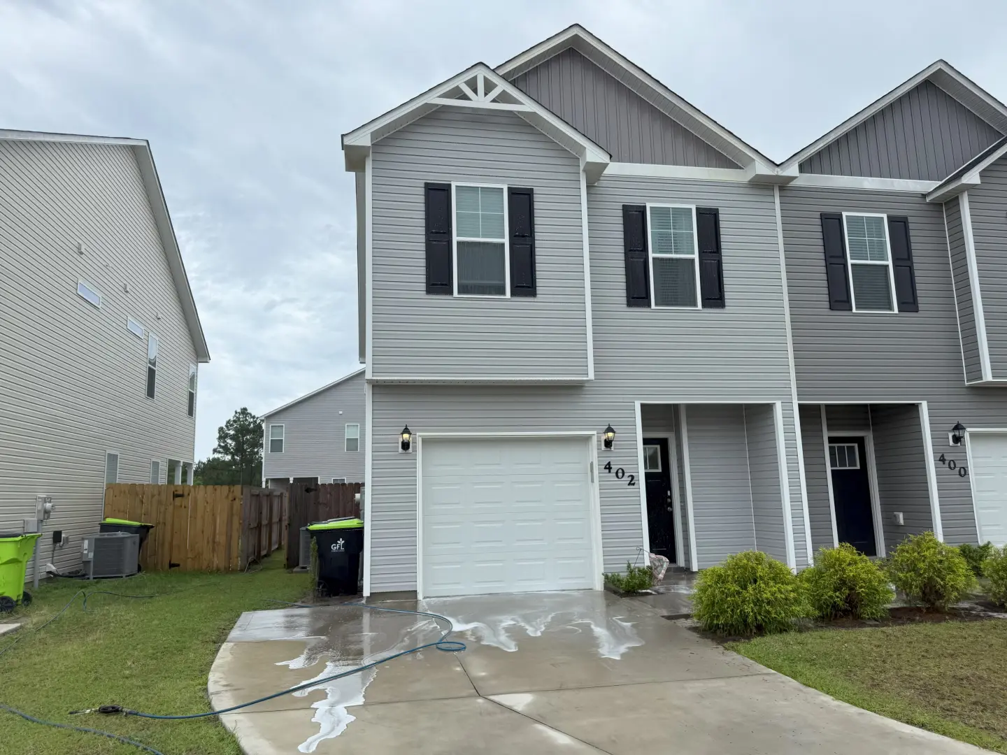 Pressure washing a residential home exterior, showcasing a freshly cleaned driveway and siding.