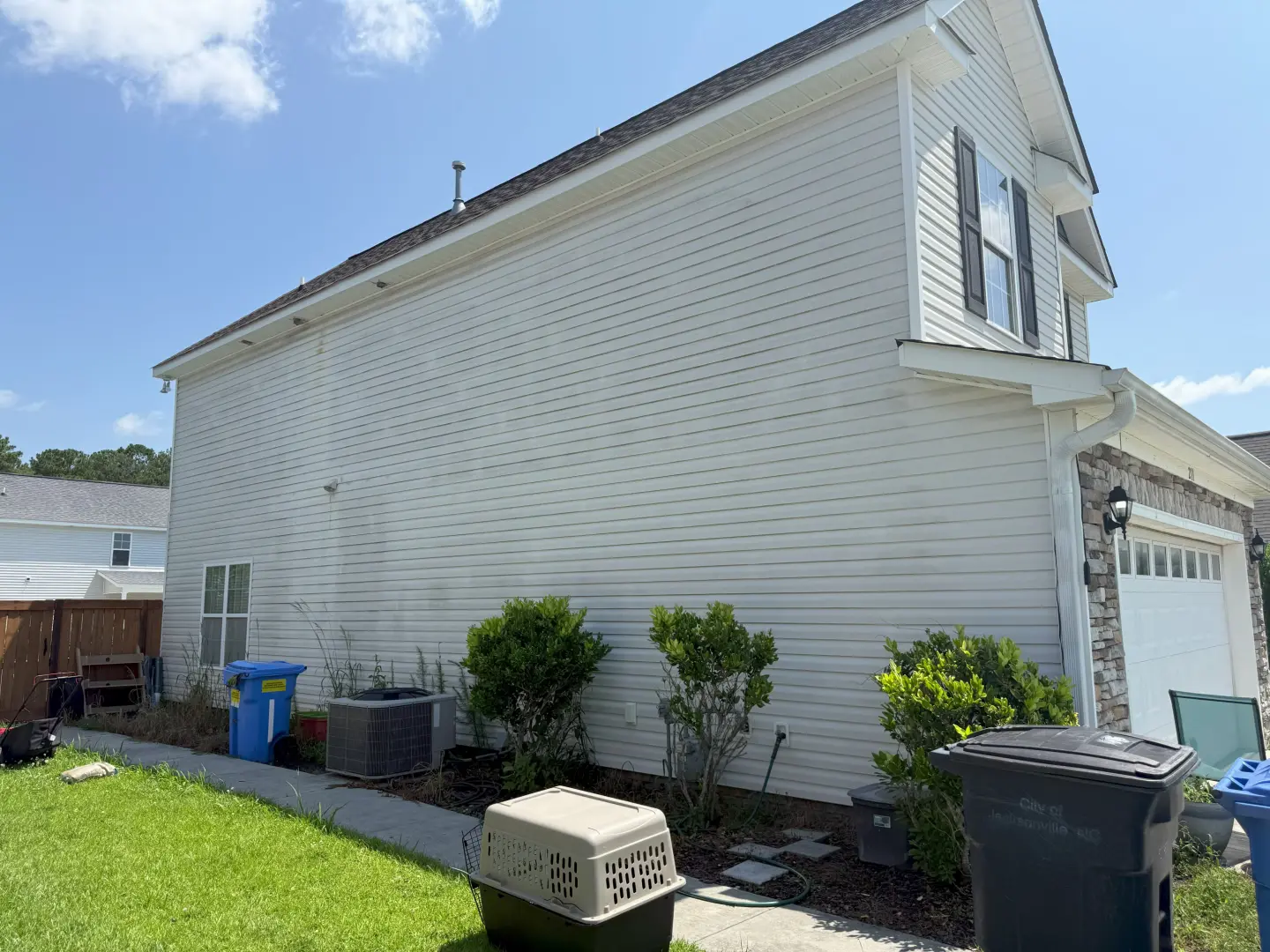 Pressure washing a vinyl siding home, showcasing a clean, dirt-free finish versus stained areas.