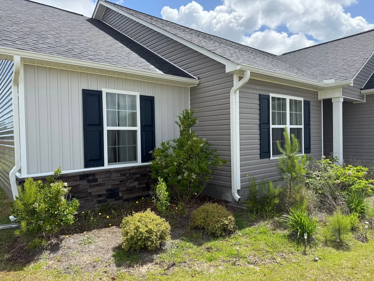 Pressure washing cleans the exterior siding of a house, revealing a fresh and vibrant appearance.