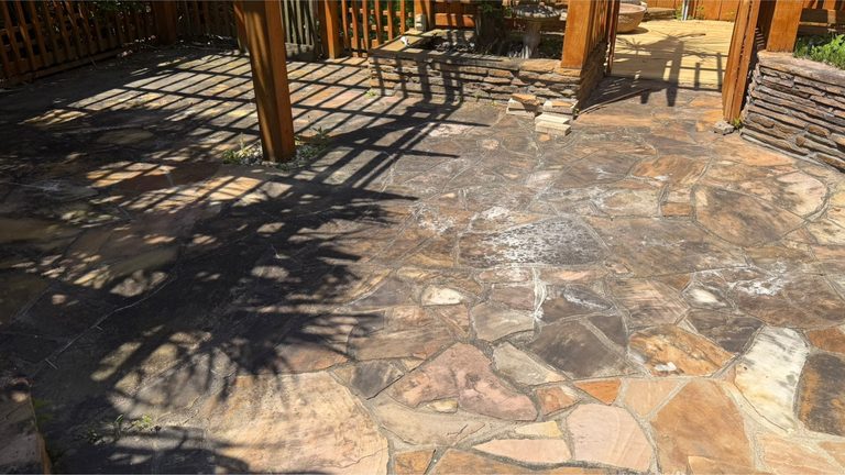 Flagstone patio and pergola dulled by organic film