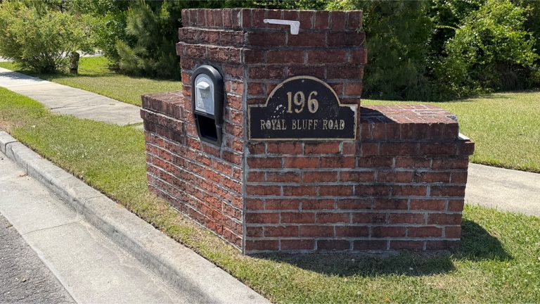 Brick community monument sign dulled by organic growth