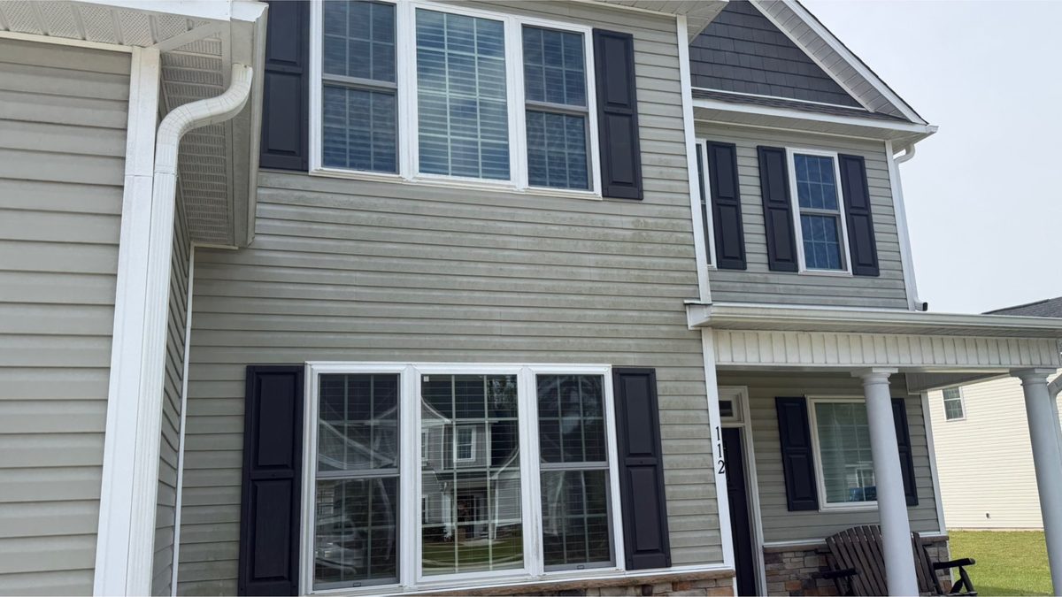 Two-storey home with siding, trim and shutters dulled by organic staining